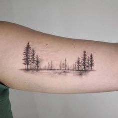 a woman's arm with trees and water on it