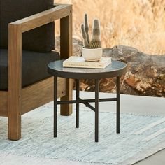 a small table with a potted cactus on it next to a chair and rug