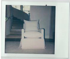 a white chair sitting in front of a stair case with pillows on top of it