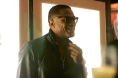 a man wearing glasses standing in front of a window