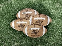 four wooden footballs sitting in the grass on top of each other with names and numbers