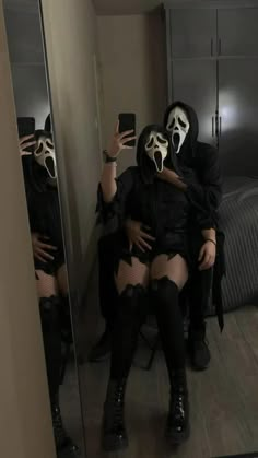 two people wearing masks are taking pictures in the mirror