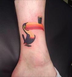 a toucan tattoo on the foot of a person with a drink in it