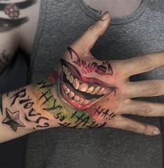 a person with tattoos on their hands and face painted to look like the joker's mouth