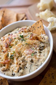 a white bowl filled with dip surrounded by crackers