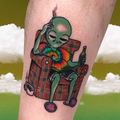 an alien sitting in a chair with a tie dye shirt on it's leg