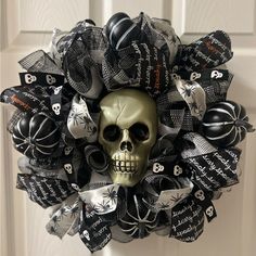 a wreath decorated with black and white halloween decorations is hanging on the front door as a skull sits in the center