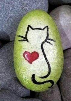 a painted rock with a cat's face on it and a heart in the middle