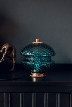 a blue vase sitting on top of a black table next to a bronze statue and lamp