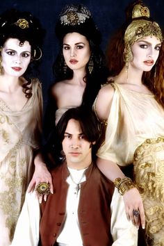 three women and one man are posing for a photo in ancient costumes, with long hair