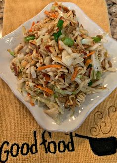 a white plate topped with noodles and veggies on top of a counter next to a towel