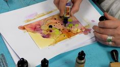 a person is painting with watercolors on paper