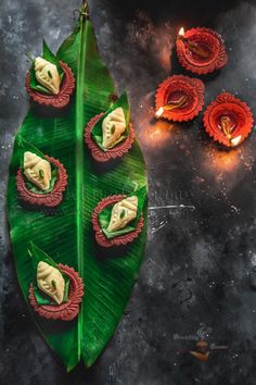 some food is sitting on top of a green leaf and lit candles are in the background