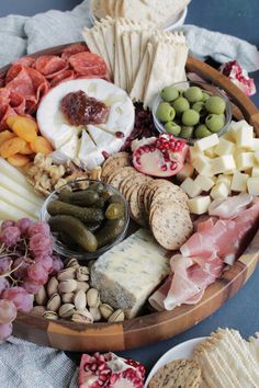 an assortment of cheeses, meats and crackers on a platter