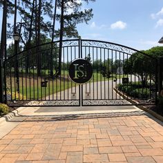 an iron gate with the number 15 on it in front of a driveway and trees