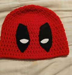 a red crocheted hat with black eyes on it