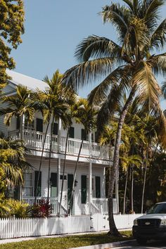 a police car parked in front of a white house with palm trees on the street