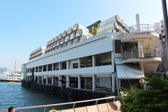 a large building sitting on the side of a body of water next to a pier