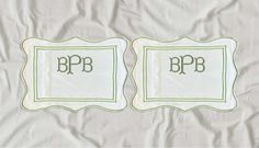 two embroidered placemats with the letters p and b in green on white paper