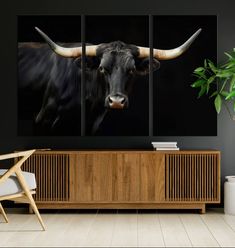 a cow with large horns standing in front of a wall mounted painting on it's side