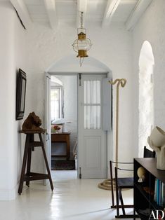 an open door leading into a room with white walls and flooring, along with a lamp