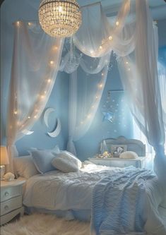 a white bed sitting under a chandelier next to a night stand with lights on it