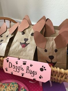 some paper bags with dogs on them are sitting in a basket next to cookies and doughnuts