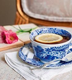 a blue and white tea cup with lemon wedges on the saucer next to it