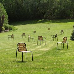 several chairs sitting in the middle of a grassy field with trees in the back ground