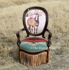 an old chair with a horse on it in the middle of a dry grass field