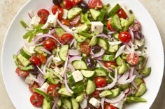 a white plate topped with cucumber, tomatoes and onions