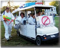 people in white suits are riding on a golf cart