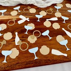 a wooden table topped with lots of paper cut outs and wine glasses on top of it