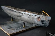 an old model of a submarine on a wooden stand with metal parts around the bottom