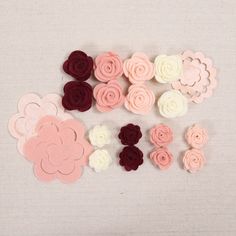 several felt flowers are arranged on a white surface with red, pink and white petals