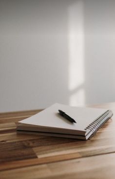 a notebook and pen sitting on top of a wooden table