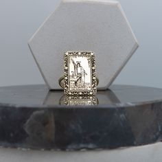 a gold ring with an image of a man on it sitting on top of a marble pedestal