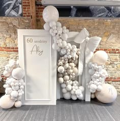 balloons are arranged in the shape of an arch with white flowers and leaves on it