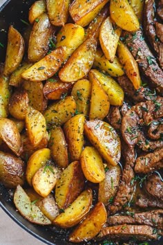 cooked potatoes and meat in a skillet with herbs on top, ready to be eaten