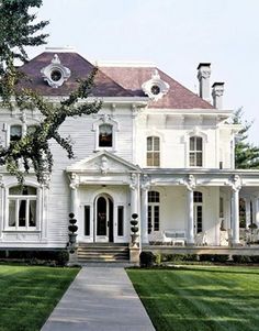 a large white house sitting on top of a lush green field