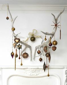 a fireplace mantel with ornaments hanging from it's sides and an antlers on the mantle