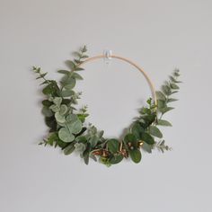 a wreath with green leaves and branches hanging on the wall