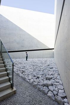 there is a man walking down the stairs in front of some rocks and stone steps