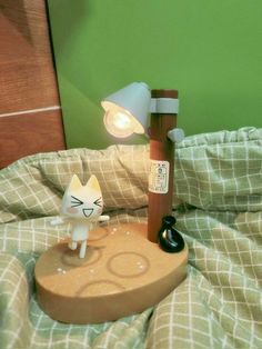 a cat lamp sitting on top of a bed next to a night stand with an alarm clock