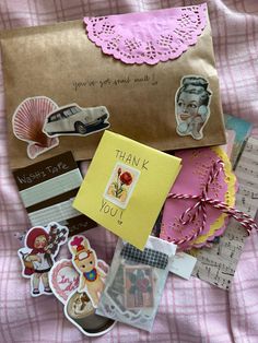 an envelope with lots of stickers on it sitting on a bed next to other items