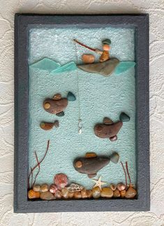 there is a sculpture made out of rocks and pebbles in the water with a man fishing