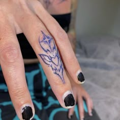 a woman's hand with an owl tattoo on her left thumb and the other half of her finger