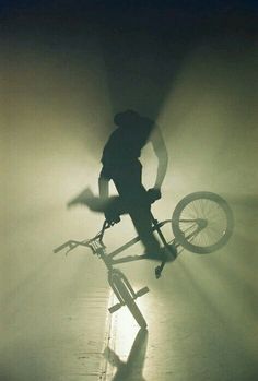 a person riding a bike in the middle of foggy area with their shadow on the ground