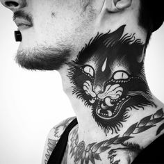 a man with a cat tattoo on his neck and chest is looking into the distance