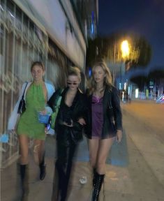 three women walking down the street at night time, one in a short dress and two in high heels